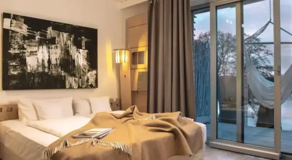 Nowoczesny pokój z dużym łóżkiem, abstrakcyjnym obrazem i widokiem na jezioro. Idealne miejsce na relaks w hotelach dla dorosłych.
