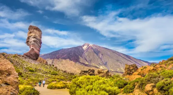 Wulkan Teide na Teneryfie, idealna pogoda w październiku. Skalny palec i para spacerująca pośród zieleni.