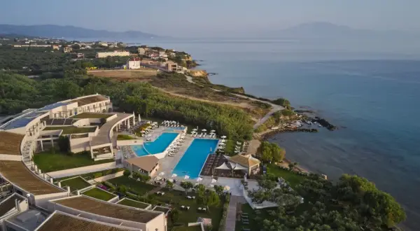 Hotel Pelagos Zante, z basenami i widokiem na morze, otoczony zielenią i gajami oliwnymi.
