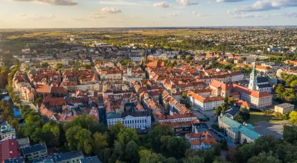 Widok z lotu ptaka na zabytkowe centrum Kalisza, najstarszego miasta w Polsce, z charakterystyczną czerwoną dachówką i wieżami kościołów.
