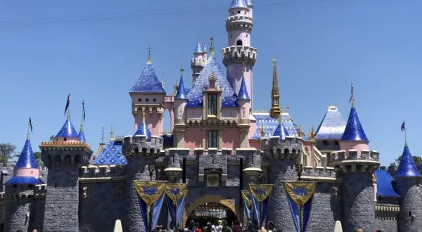 Bajkowy zamek z niebieskimi dachami, jak w Disneylandzie w Polsce. Tłum ludzi przed wejściem.