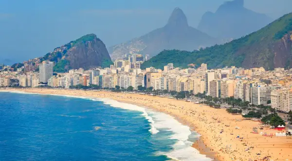 Copacabana w Rio de Janeiro, z tłumami na plaży i górami w tle. Zastanawiasz się, czy do Brazylii potrzebna jest wiza?