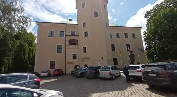 Zamek w Redzikowie, z wieżą i parkingiem przed wejściem.