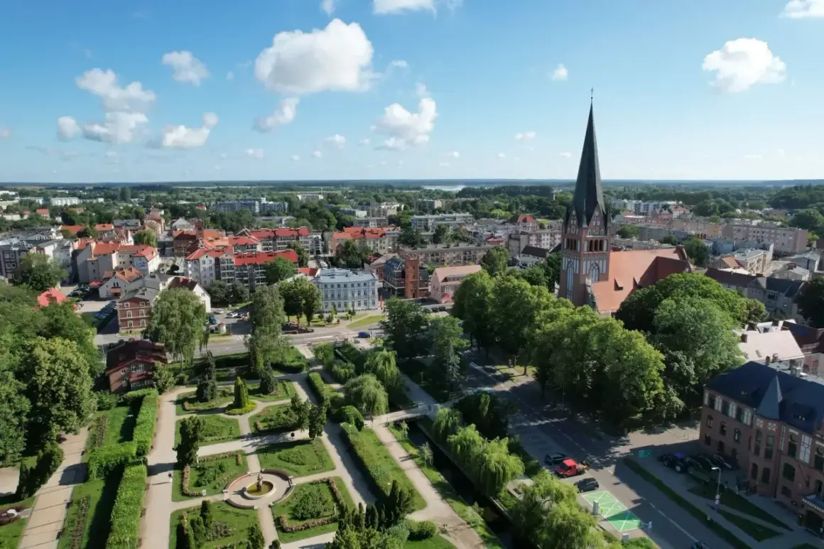 Widok na miasto z wieżą kościelną i parkiem. W oddali widać jezioro. Wieża Bismarcka w Szczecinku nie jest widoczna na tym ujęciu.