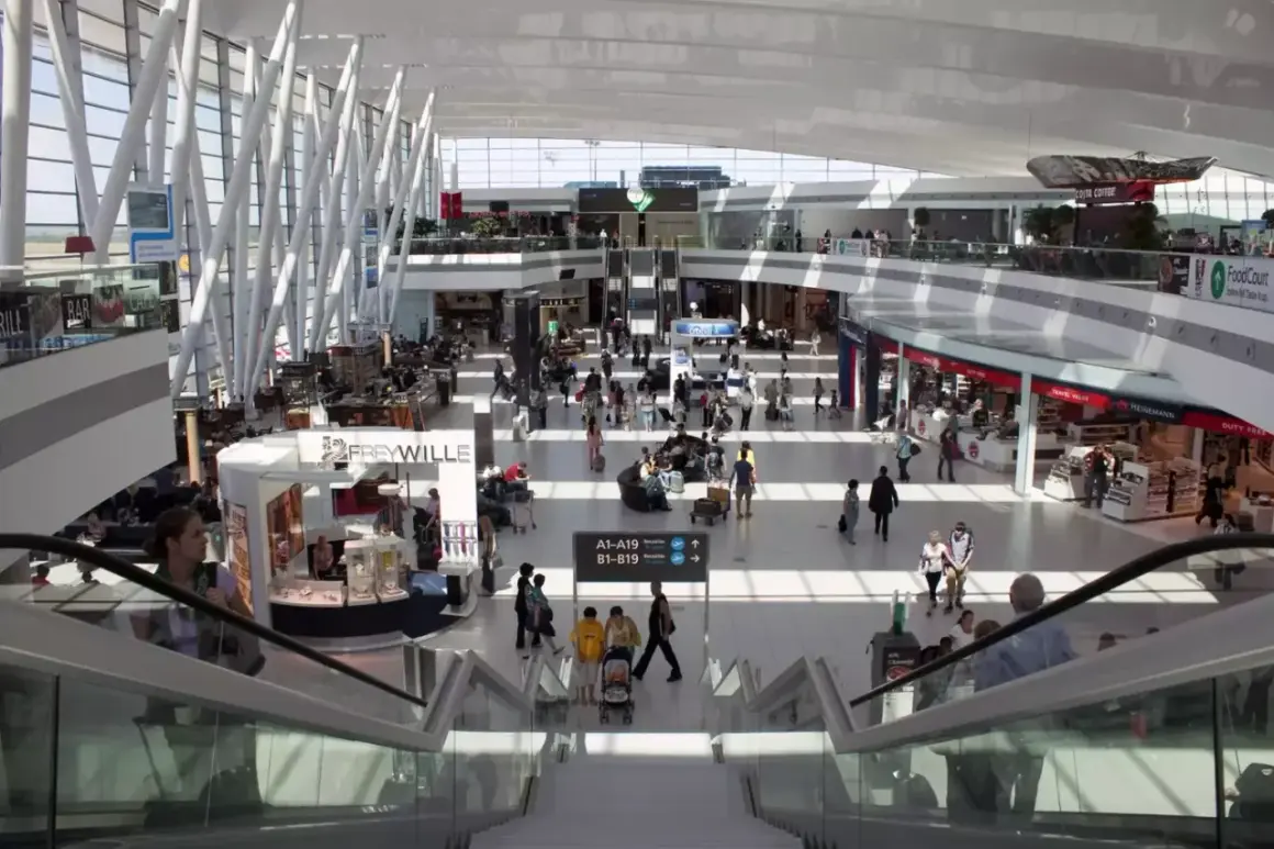 Tętniący życiem terminal lotniska w Budapeszcie. Pasażerowie przemieszczają się między sklepami i kawiarniami, a nowoczesna architektura tworzy przestronne wnętrze.
