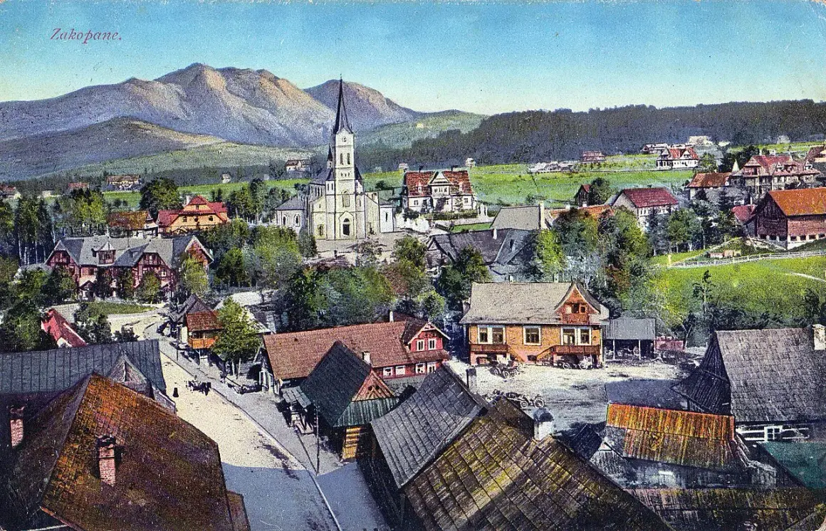 Widok na Zakopane z górami w tle, kościołem i tradycyjnymi willami.