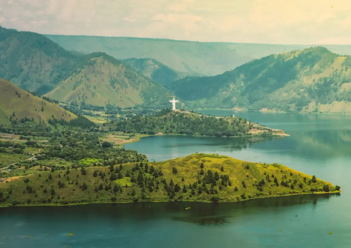 Malownicza wyspa w Indonezji z górami w tle i pomnikiem Chrystusa Króla.