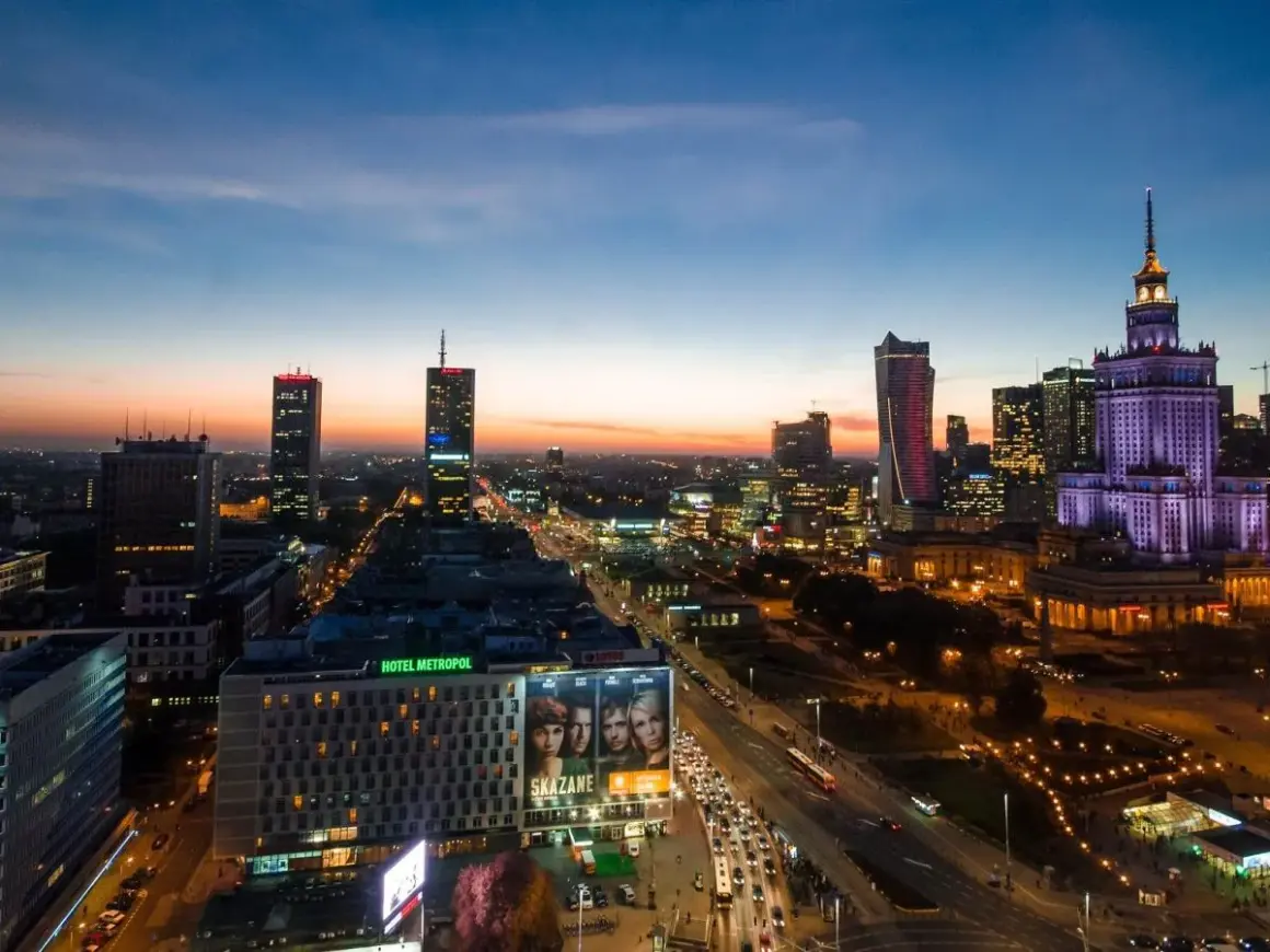 Wieczorna panorama Warszawy, największego miasta w Polsce. Widać Pałac Kultury i Nauki, nowoczesne wieżowce i ruchliwe ulice.