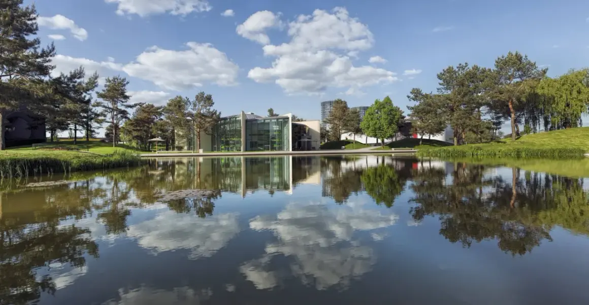 Nowoczesne budynki z zielonymi akcentami odbijają się w spokojnej tafli wody. To malownicze **Wolfsburg miasto**, gdzie natura harmonijnie współgra z architekturą.