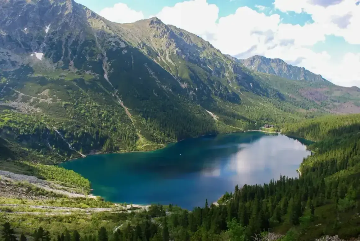 Malowniczy szlak na Morskie Oko prowadzi przez gęsty las do turkusowego jeziora otoczonego skalistymi szczytami Tatr.