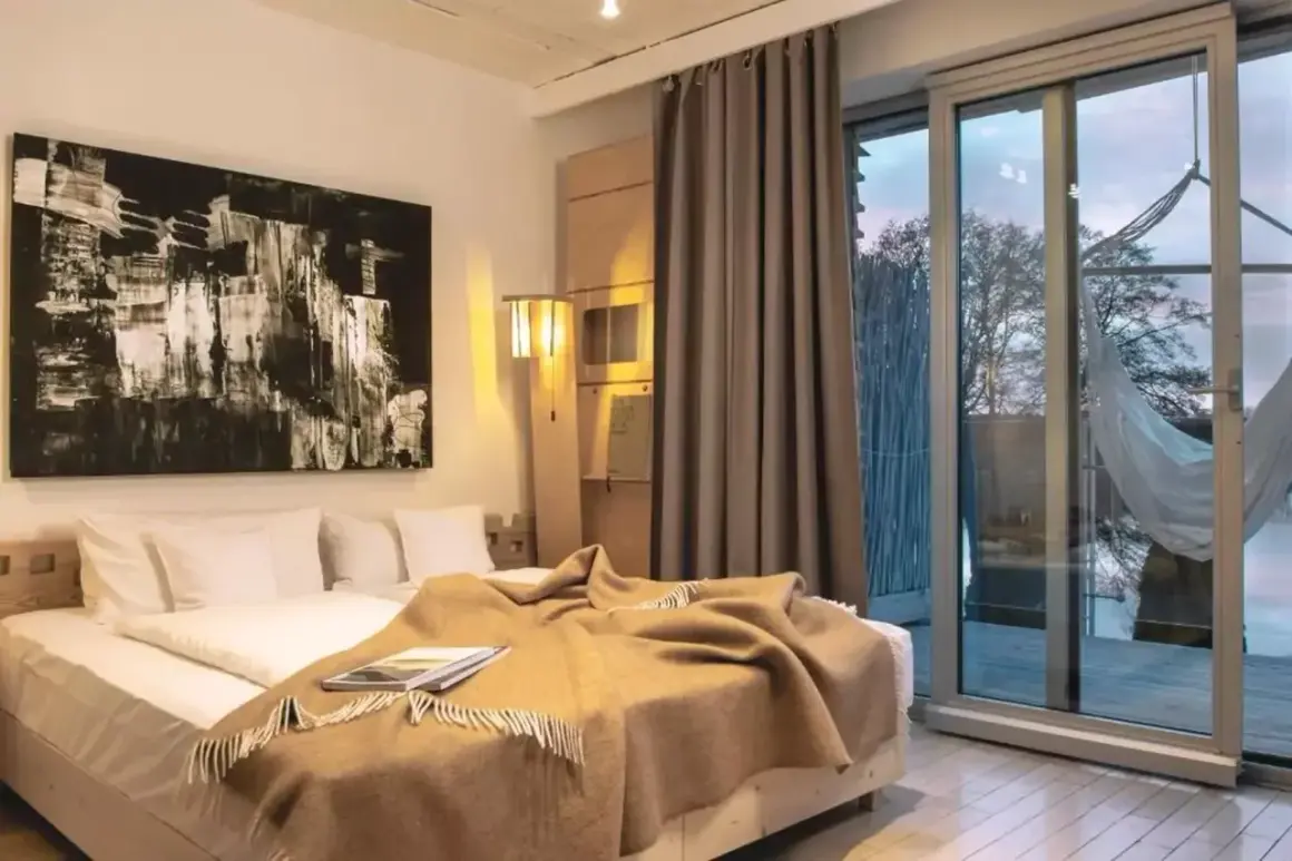 Nowoczesny pokój z dużym łóżkiem, abstrakcyjnym obrazem i widokiem na jezioro. Idealne miejsce na relaks w hotelach dla dorosłych.