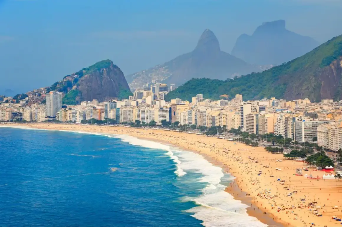 Copacabana w Rio de Janeiro, z tłumami na plaży i górami w tle. Zastanawiasz się, czy do Brazylii potrzebna jest wiza?