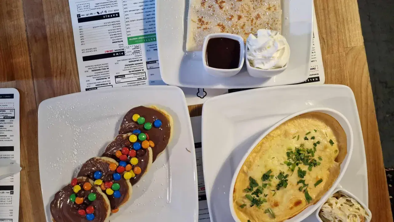 Pankejk menu: słodkie placuszki z czekoladą i kolorowymi drażetkami, obok naleśnik z polewą i bitą śmietaną.