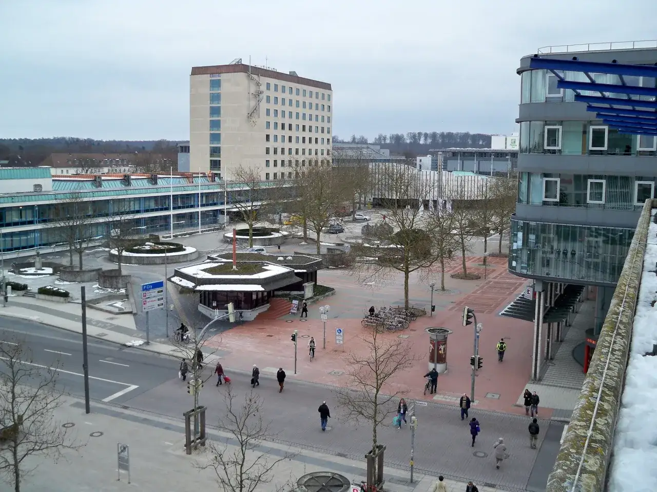 Widok na plac miejski w Wolfsburg. Miasto tętni życiem, ludzie spacerują, jeżdżą na rowerach.