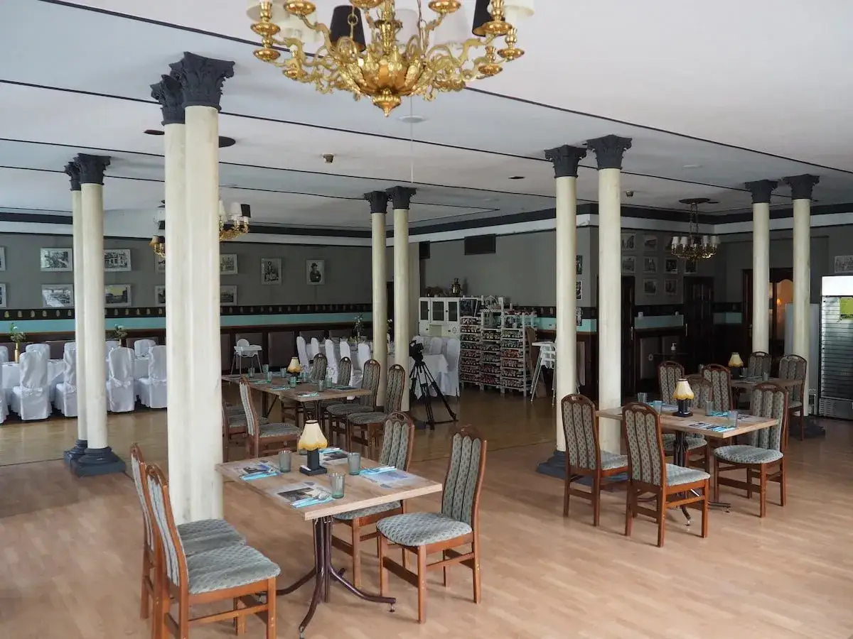 Wnętrze restauracji z kolumnami i stołami, gdzie stara łaźnia kuchenne rewolucje nabiera nowego blasku.