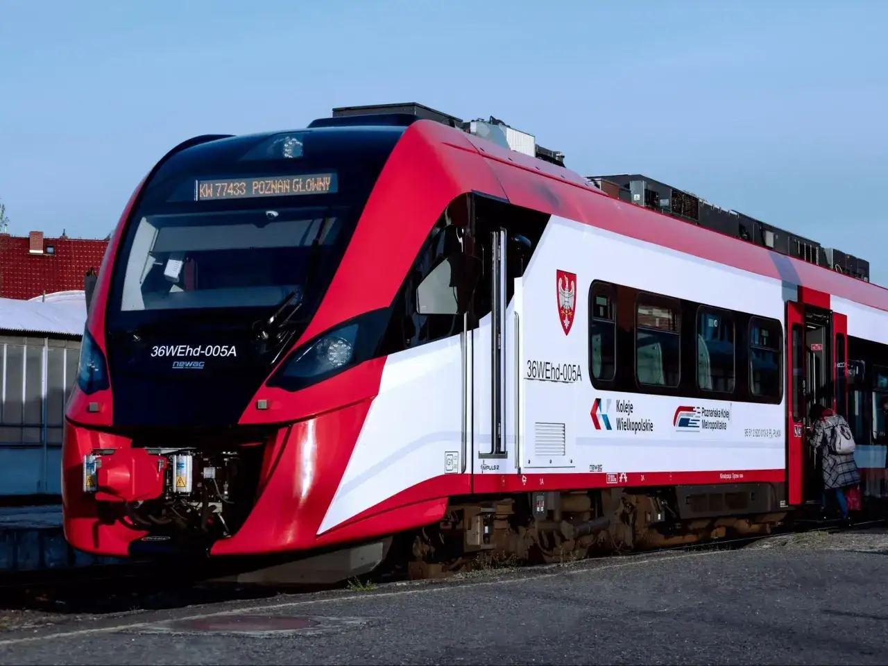 Czerwono-biały pociąg Kolei Wielkopolskich z napisem 