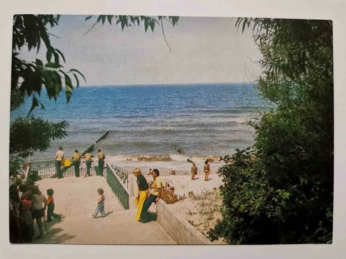 Ludzie spacerują przy plaży w Jarosławcu, w tle widać morze i falochrony.