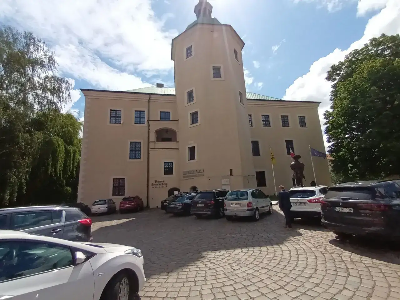 Zamek w Redzikowie, z wieżą i parkingiem przed wejściem.