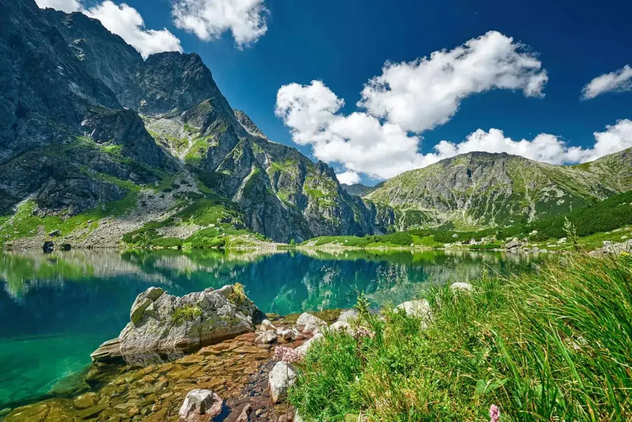 Tatry oferują najpiękniejsze szlaki w tatrach dla początkujących. Jezioro Morskie Oko odbija majestatyczne szczyty w błękitnym niebie.