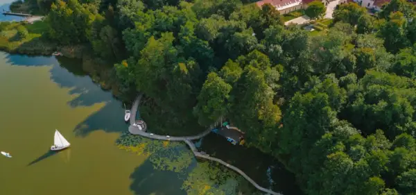 Malownicze jezioro w Torzymiu z żaglówką, drewnianym pomostem i otaczającym lasem.