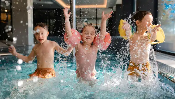 Dzieci bawią się w basenie hotelu z aquaparkiem w górach, chlapiąc wodą i ciesząc się wakacjami.