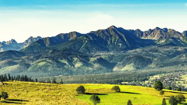 Sierockie widoki na Tatry z zielonymi łąkami i lasami.