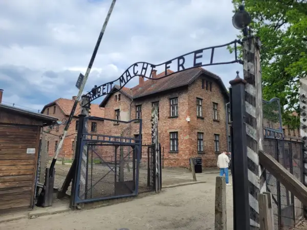 Brama z napisem "Arbeit Macht Frei" prowadzi do budynków obozu Auschwitz.