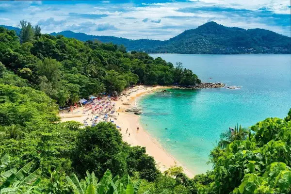 Rajska plaża Kata Beach z turkusową wodą, zielonymi wzgórzami i mnóstwem kolorowych parasoli.
