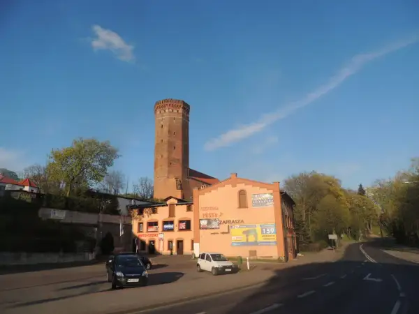 Wieża w Kamieniu Krajeńskim góruje nad budynkami z pizzerią i sklepem.