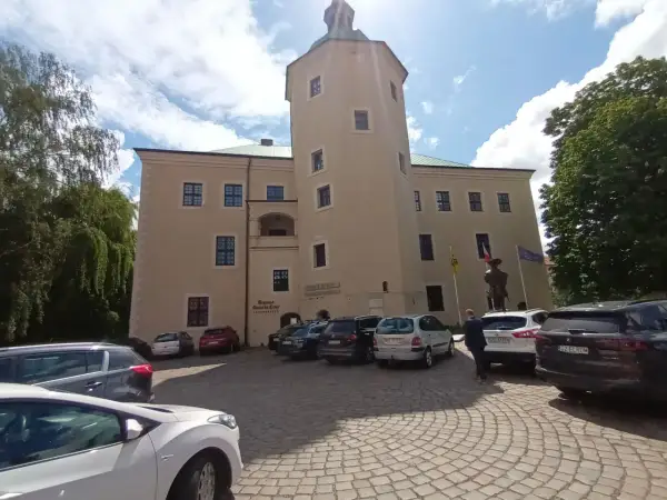 Zamek w Redzikowie, z wieżą i parkingiem przed wejściem.